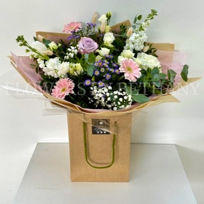 Hand tied bouquet in soft pinks, lilac and white, including roses, stocks, germini, bunny tail and other mixed varieties. 