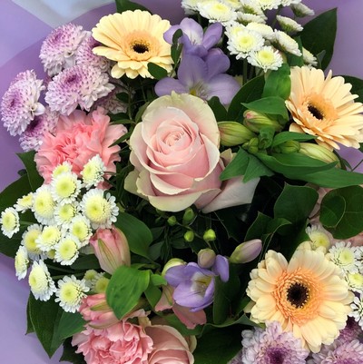 Hand tied bouquet of pastel tones including roses, carnations, chrysanthemums and freesia. 