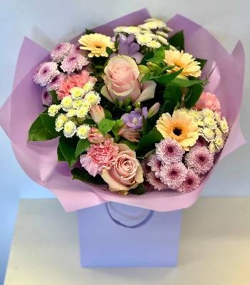 Hand tied bouquet of pastel tones including roses, carnations, chrysanthemums and freesia. 