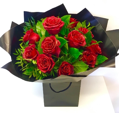 Luxury gift bouquet of freedom glittered red roses wrapped in matching cellophane and gift bag. 