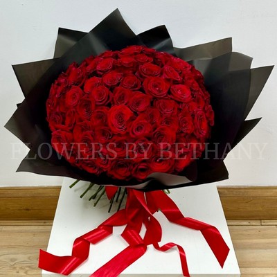 Hand-tied bouquet of 100 luxury large-headed red Freedom roses, wrapped in frosted black cellophane with a large red satin ribbon, and delivered with a FREE XL glass vase. Size: 24 x 24 Inch.