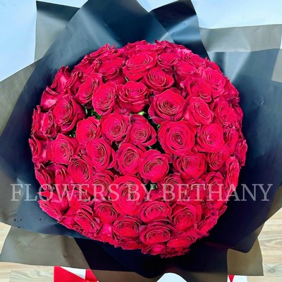 Hand-tied bouquet of 100 luxury large-headed red Freedom roses, wrapped in frosted black cellophane with a large red satin ribbon, and delivered with a FREE XL glass vase. Size: 24 x 24 Inch.