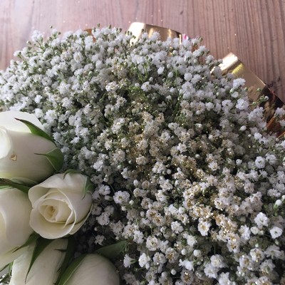 Massed gypsophila funeral heart tribute sprinkled with gold glitter and gold ribbon edge. 