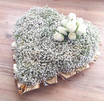 Massed gypsophila funeral heart tribute sprinkled with gold glitter and gold ribbon edge. 