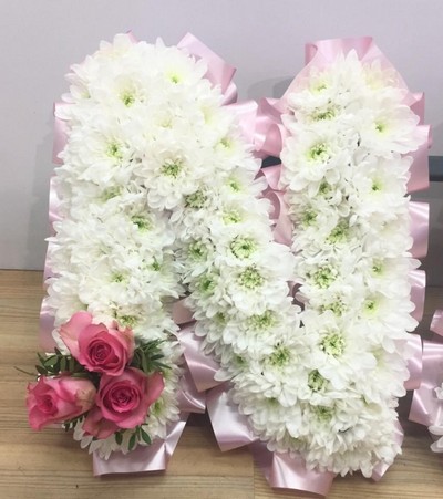 Ribbon edged NANA funeral tribute with pale pink rose focal. 