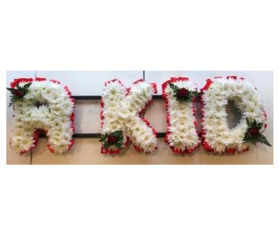 R KID Funeral lettering in traditional white massed chrysanthemum and red ribbon edge and focal. 