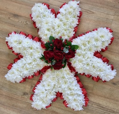 Maltese cross funeral tribute with massed white chrysanthemum and red focal and ribbon edge. 