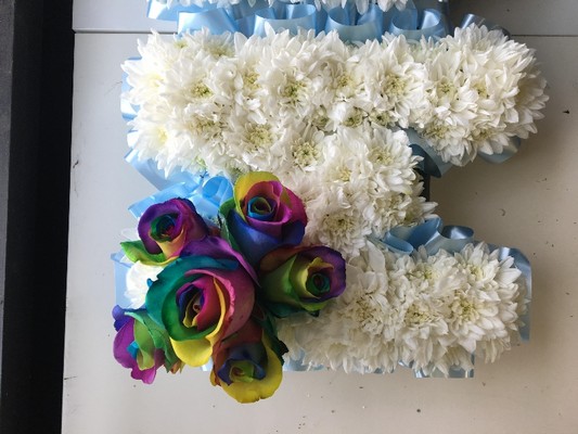 Rainbow focal MUM funeral tribute with white chrysanthemum base. 