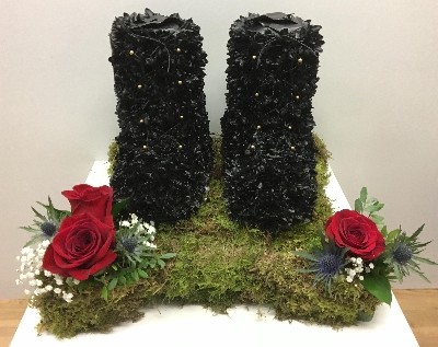 Black army boots funeral tribute with moss base and gold buckle detailing. 