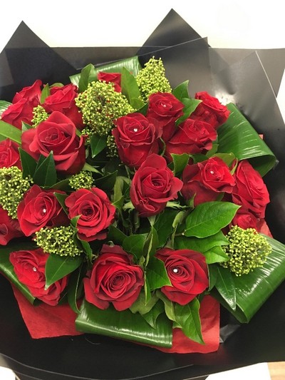 Luxury bouquet featuring large-headed red roses, skimmia, aspidistra folded leaves, and diamanté centres, wrapped in luxury cellophane and presented in a matching hat box, hand-tied in water.