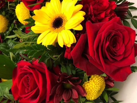 Red and yellow funeral wreath with seasonal flowers and foliage, a fitting tribute for any Manchester United fan.