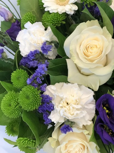 Hand tied bouquet including mondial white roses, purple Lizianthus, Kermit chrysanthemum and a mix of other fresh toned flowers. 