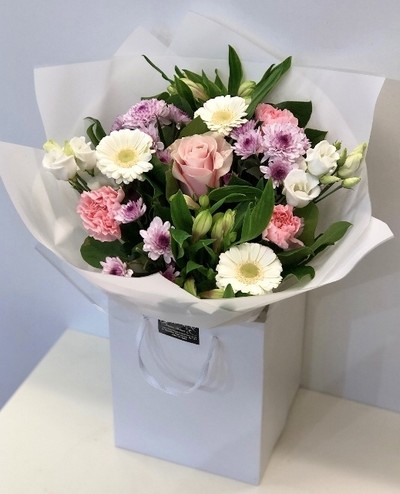 Hand tied bouquet of soft tones, includes roses, carnation, chrysanthemums and germini. 