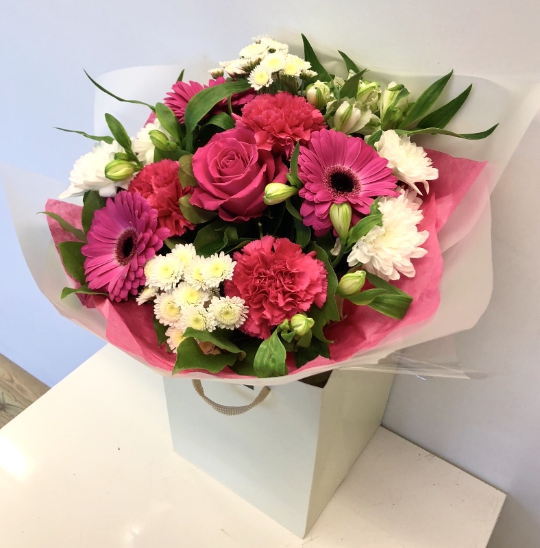 Bright bouquet in cerise and white including roses, gerbera, carnation and chrysanthemums. Hand tied in water.