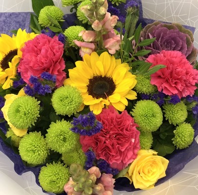 Hand tied bouquet in water with a vivid mix of colour including roses, carnation, chrysanthemums and brassica. 