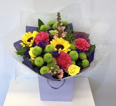 Hand tied bouquet in water with a vivid mix of colour including roses, carnation, chrysanthemums and brassica. 