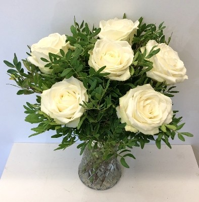 White rose bouquet displayed in a glass vase with zero plastic. 