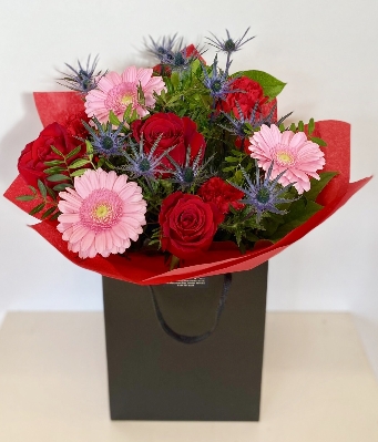 Mixed bouquet with red roses, blue thistle and pink germini. 