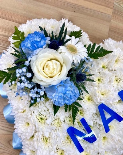 Heart-shaped funeral tribute with laminated wording, white chrysanthemums, delicate ribbon edge, and matching focal. Customizable colour options available.