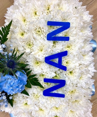Heart-shaped funeral tribute with laminated wording, white chrysanthemums, delicate ribbon edge, and matching focal. Customizable colour options available.