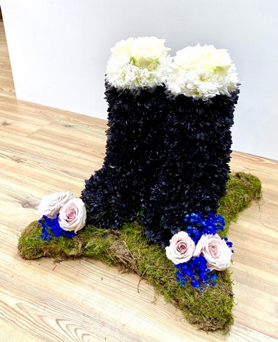 Wellington Boot funeral tribute on a moss base with black and white wellington boots