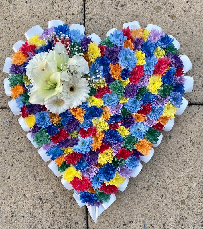 Beautiful speckled rainbow heart funeral tribute made with chrysanthemum and finished with a white ribbon edge and focal. 