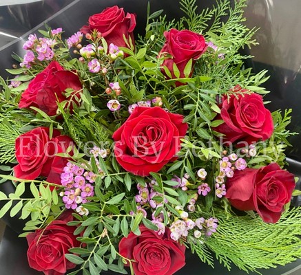 Bouquet of nine luxury red Freedom roses with pink wax flowers, accented with diamanté and complementary foliage, wrapped in luxury cellophane and matching gift bag, hand-tied in water.