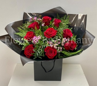 Bouquet of nine luxury red Freedom roses with pink wax flowers, accented with diamanté and complementary foliage, wrapped in luxury cellophane and matching gift bag, hand-tied in water.
