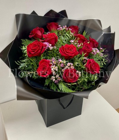 Dozen luxury red roses with fresh-scented wax flowers, accented with diamanté and complementary foliage, wrapped in luxury cellophane and matching gift bag, hand-tied in water.