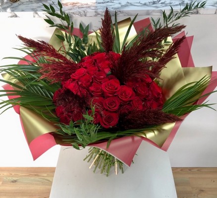 The ultimate gift of 50 Luxury red roses, adorned with pampas grass and high end foliage, wrapped in gold metallic cellophane, hand tied in water. 