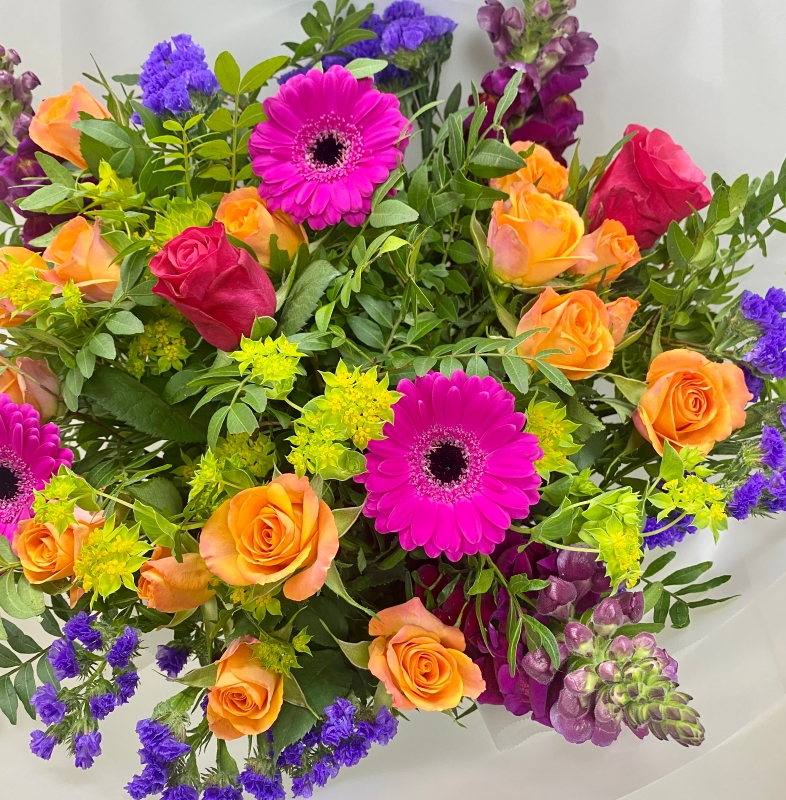 Hand tied bouquet in water including cerise germini, orange spray rose and purple snapdragons. 