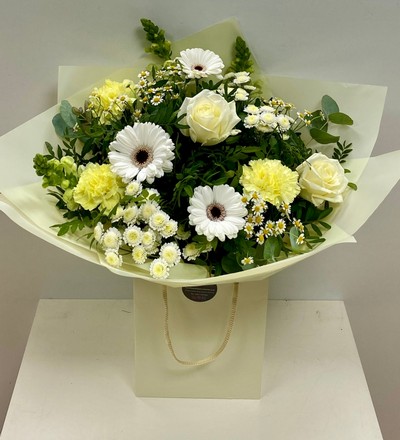 Soft yellow, cream and white toned bouquet filled with roses, carnations, germini and snapdragons hand tied in water. 