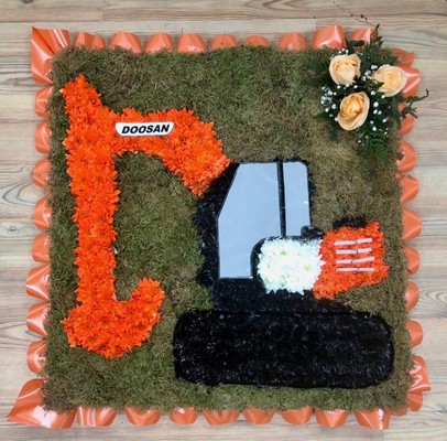 Doosan digger funeral tribute with vivid orange chrysanthemum on a moss board and finished with printed detailing. 