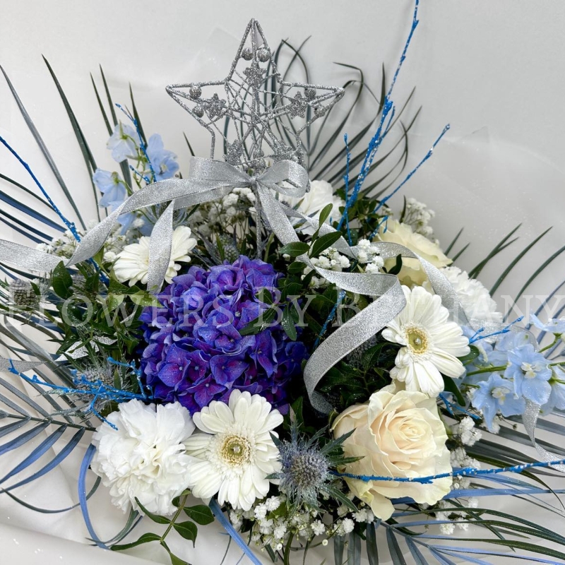Stunning frozen themed bouquet filled with fresh florals. Design includes blue thistle, white germini, white rose, blue delphinium, blue hydrangea, white gypsophila, white carnations, palm leaves and finished with a removable silver star wand.
