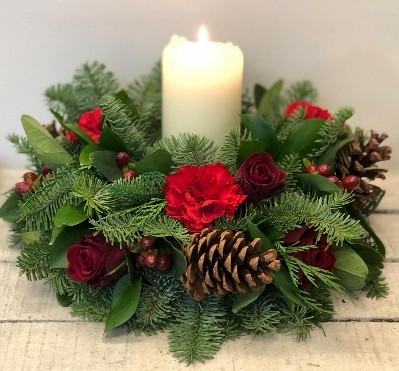 Festive table arrangement with warm red tones and candle. 