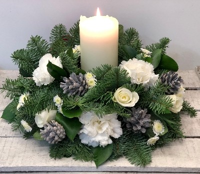 Festive table arrangement with white flowers and finished with a candle. 