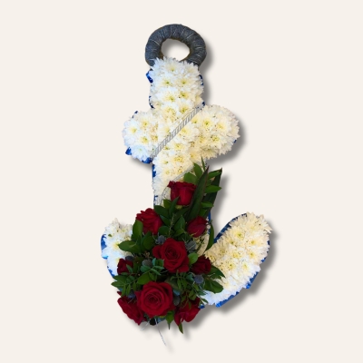 Anchor funeral tribute with white chrysanthemums, red focal flowers, and blue ribbon edge