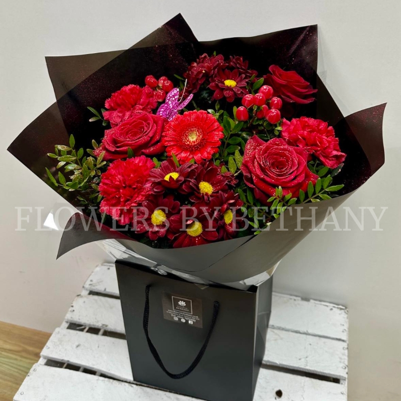 Gift bouquet in water including large red roses and red carnations finished with glitter and butterflies. 