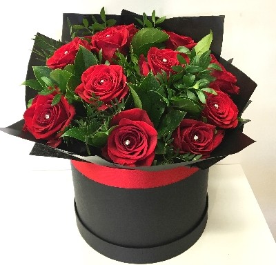 Twelve luxury large-headed red roses with complementary foliage and diamante centres, wrapped in matte black cellophane and presented in a signature matte black hat box. Also available in an 18-rose option.