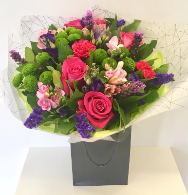 Hand tied bouquet in pinks and purples including roses, alstroemeria and statice. 