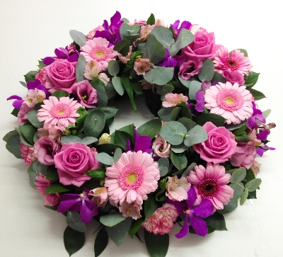 Bright pink wreath including roses, orchids and germini. 