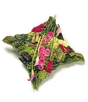 Contemporary cushion funeral tribute with roses, calla lily and mixed foliage. 