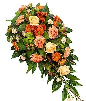 Orange and peach single-ended funeral spray with dracaena and seasonal foliage.