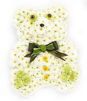 Sitting teddy bear funeral tribute created with massed white chrysanthemums. 