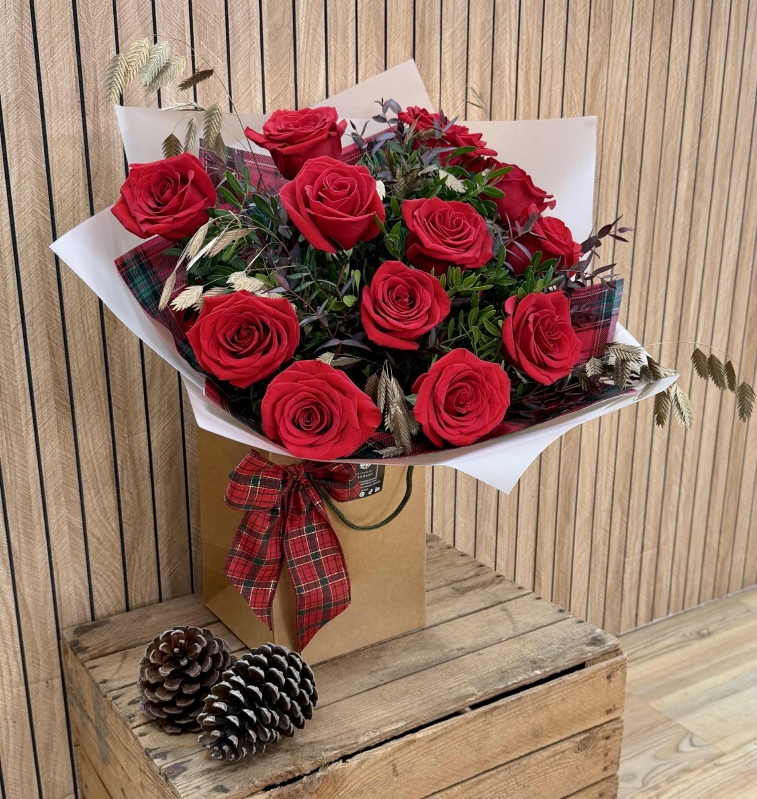 Luxury red rose Christmas bouquet with winter foliage and tartan festive accents.