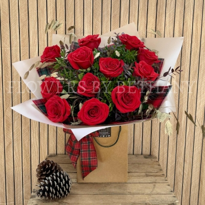 Luxury red rose Christmas bouquet with winter foliage and tartan festive accents.