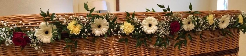 Delicate foliage and seasonal florals garland for wicker casket, customizable in colour and fullness.