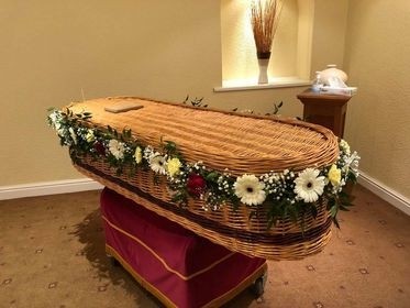 Delicate foliage and seasonal florals garland for wicker casket, customizable in colour and fullness.