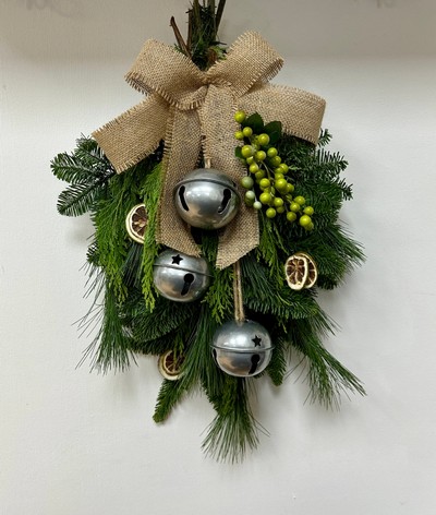 Natural door swag filled with winter foliage, green berries, lime slices, silver bells and a hessian bow. 