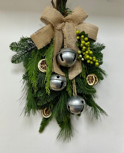Natural door swag filled with winter foliage, green berries, lime slices, silver bells and a hessian bow. 